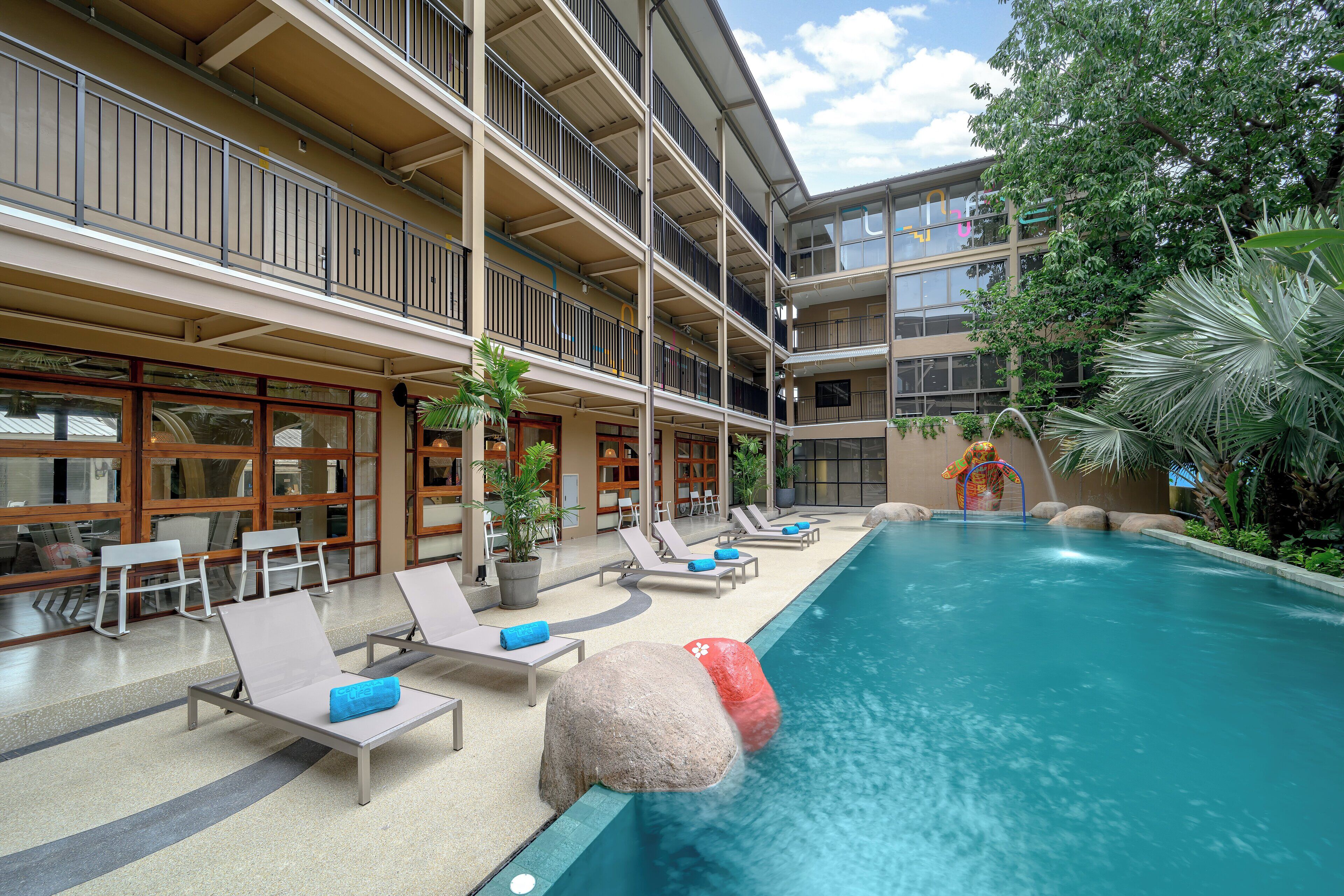 Un hôtel doté d’une piscine, de chaises longues et d’un élément décoratif aquatique.