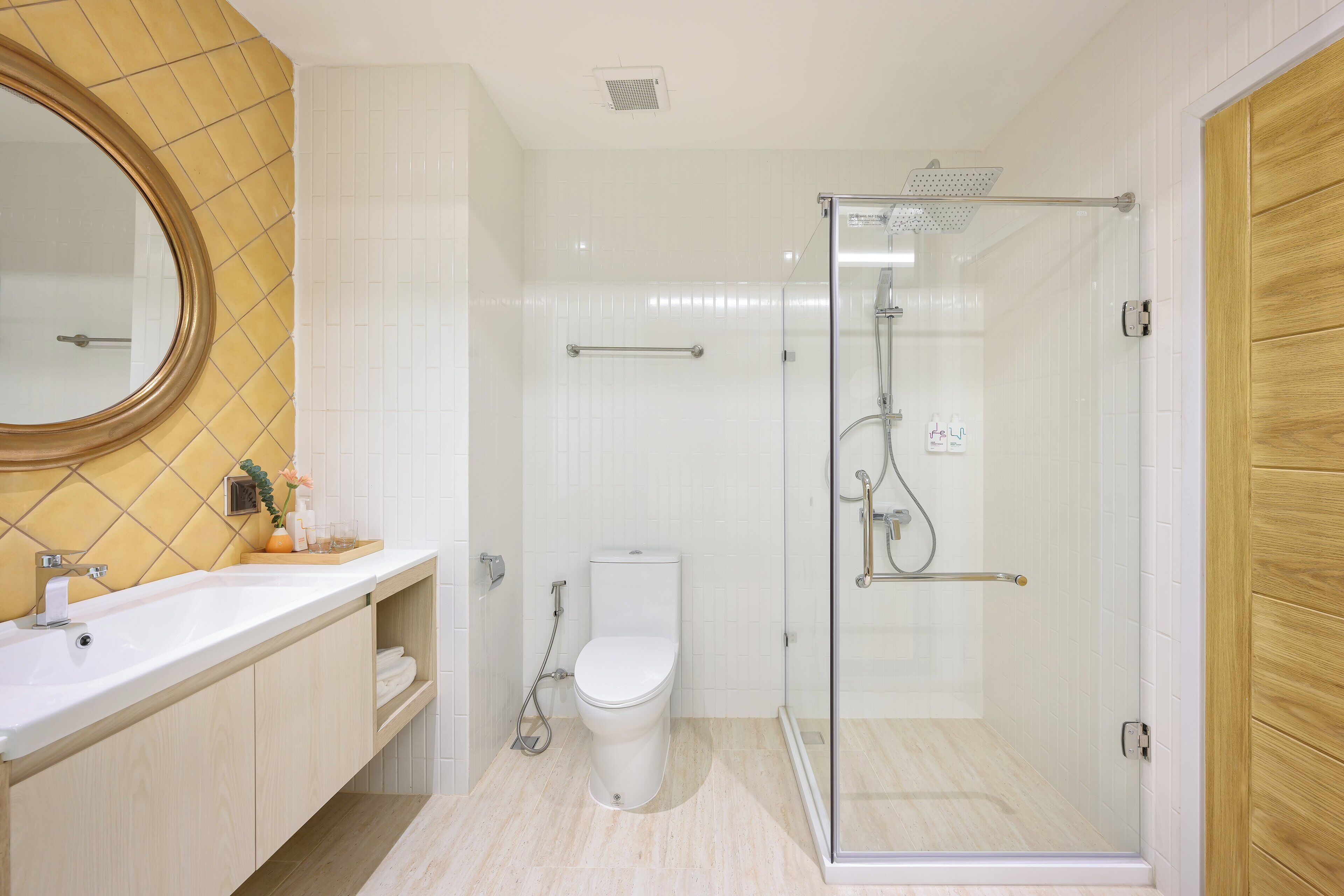 A modern bathroom with a glass shower enclosure, a white toilet, and a sink with a mirror above it.