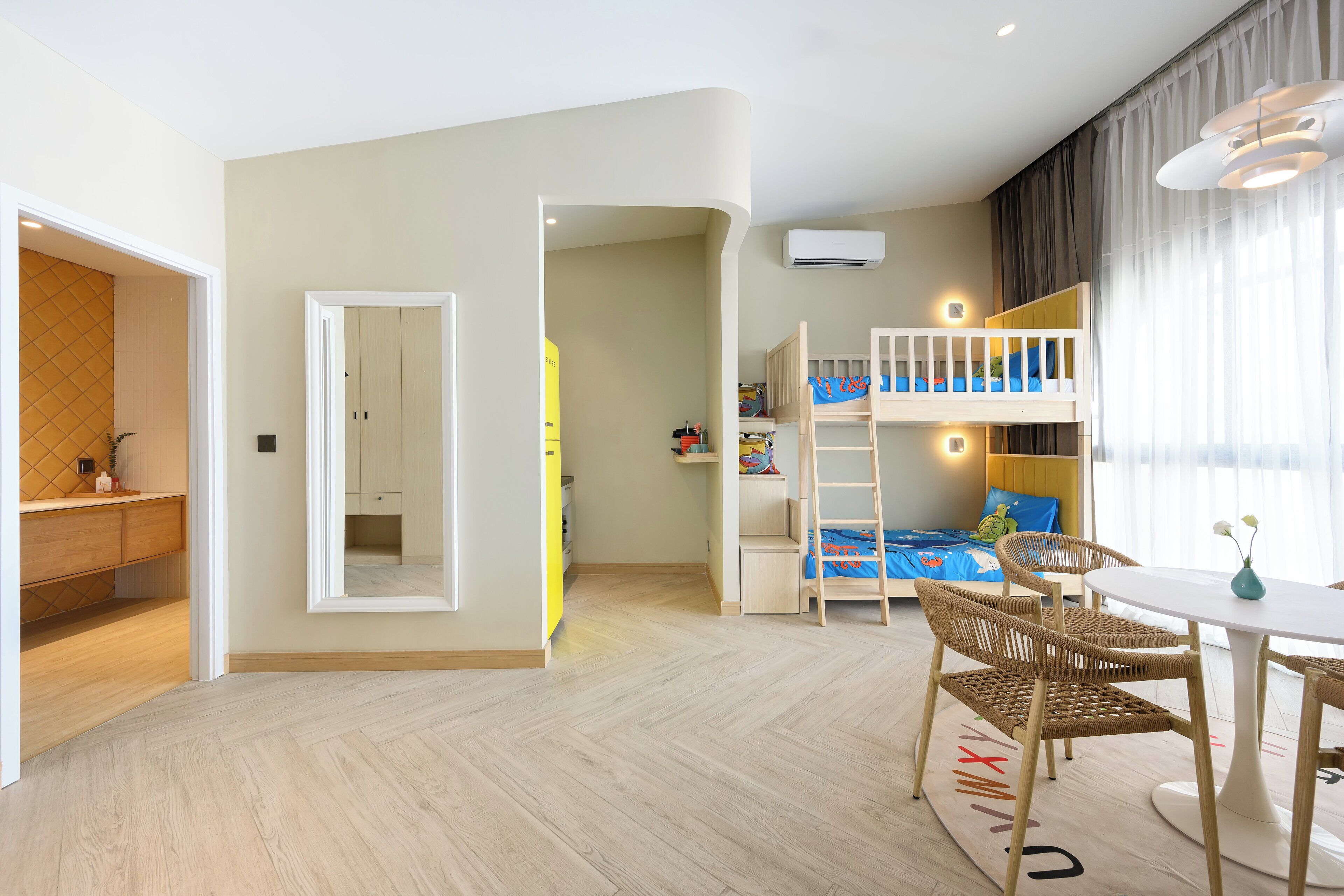 A modern, well-lit room with a bunk bed, a dining area with a table and chairs, and a kitchen area with a counter and cabinets.