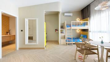 A modern, well-lit room with a bunk bed, a dining area with a table and chairs, and a kitchen area with a counter and cabinets.