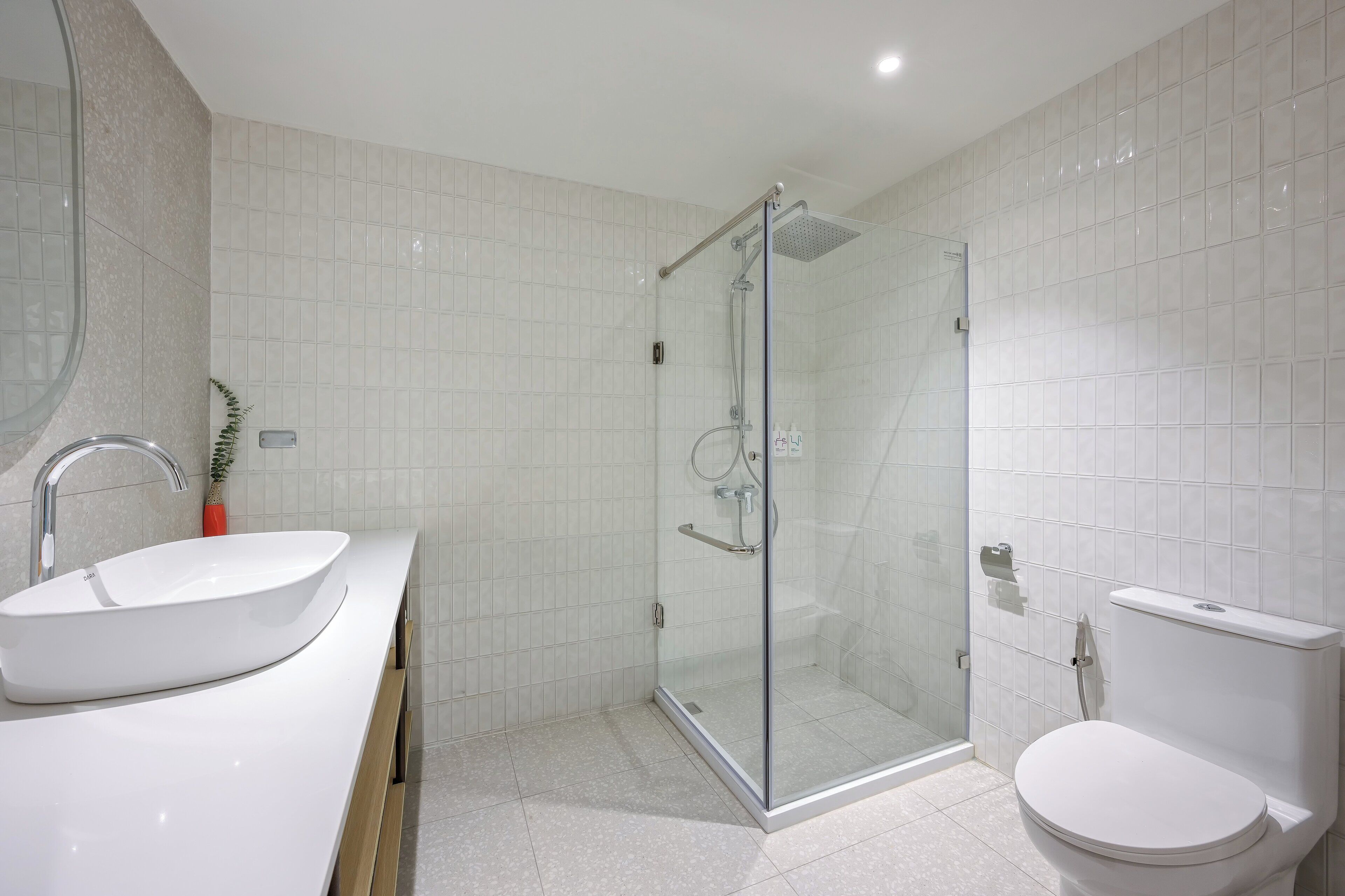 Un baño moderno con ducha de vidrio, lavamanos blanco y retrete.