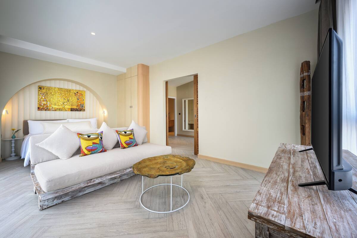 A modern bedroom with a large bed, a wooden coffee table, and a TV on a wooden stand.