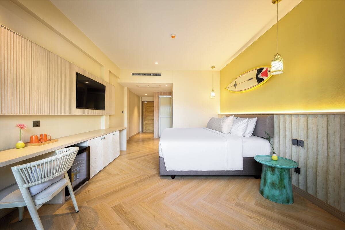A modern hotel room with a bed, a desk, and a chair.