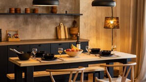 A modern kitchen with dark cabinetry, a wooden island, and pendant lighting. - Lepanto Xenia Apartments 3F (Nafpaktos)