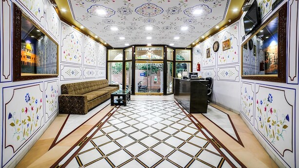 Un hall d’entrée avec un sol à motifs, un canapé, un comptoir d’accueil et une vue sur l’extérieur grâce à une porte vitrée.