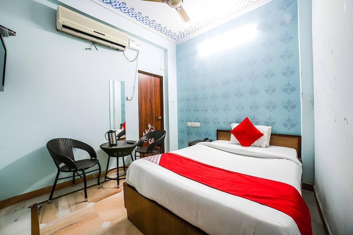 Una habitación de hotel con cama, escritorio, silla y aire acondicionado.