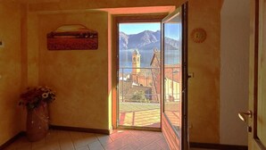 Quarto com vista para um lago e montanhas, uma porta, um vaso com flores e um quadro na parede.