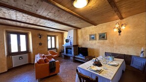 Um quarto acolhedor com lareira, uma mesa de jantar posta para dois e um sofá confortável.
