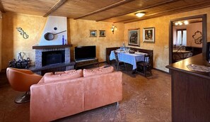 A cozy living room with a fireplace, a television, a dining table, and a sofa.