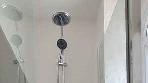 En moderne bruser med glasvægge, håndbruser og brusearm på væggen.