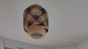Et moderne køkken med lyse skabe, en grøn stol og en flettet pendel.
