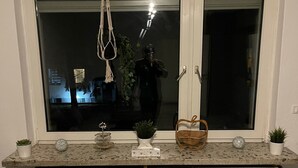 A room with a large window, a radiator below, and a small table with decorative items. - Gemütliche 3 Zimmer Wohnung in Wolfenbüttel Linden (Wolfenbüttel)