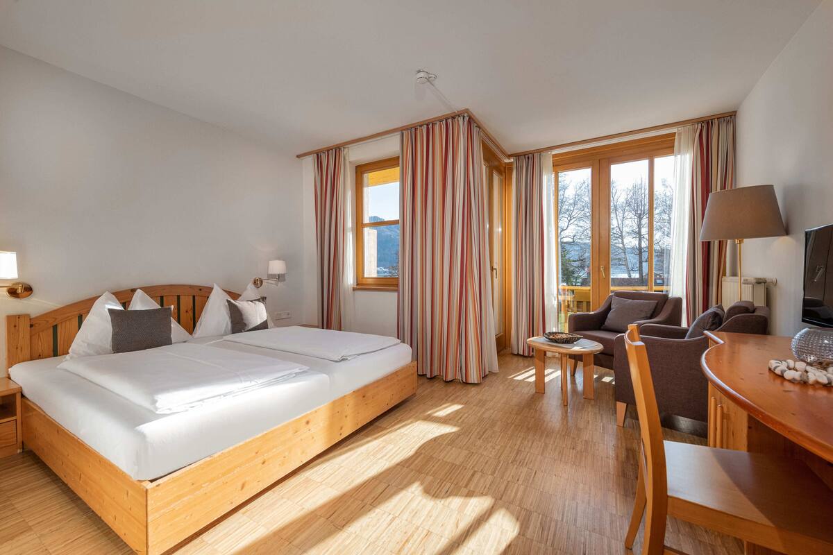 Een hotelkamer met een houten bed, een tafeltje, een sofa en een televisie.