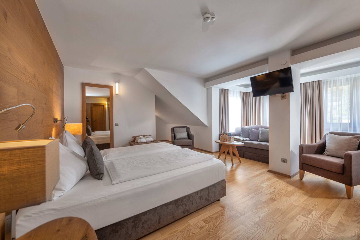Een moderne hotelkamer met een groot bed, een televisie, een bank en een bureau.