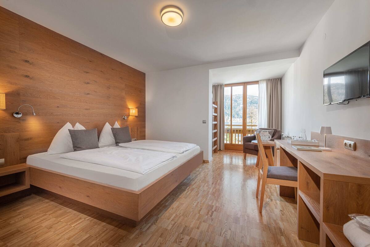 Een moderne hotelkamer met een houten bed, een bureau en een televisie.