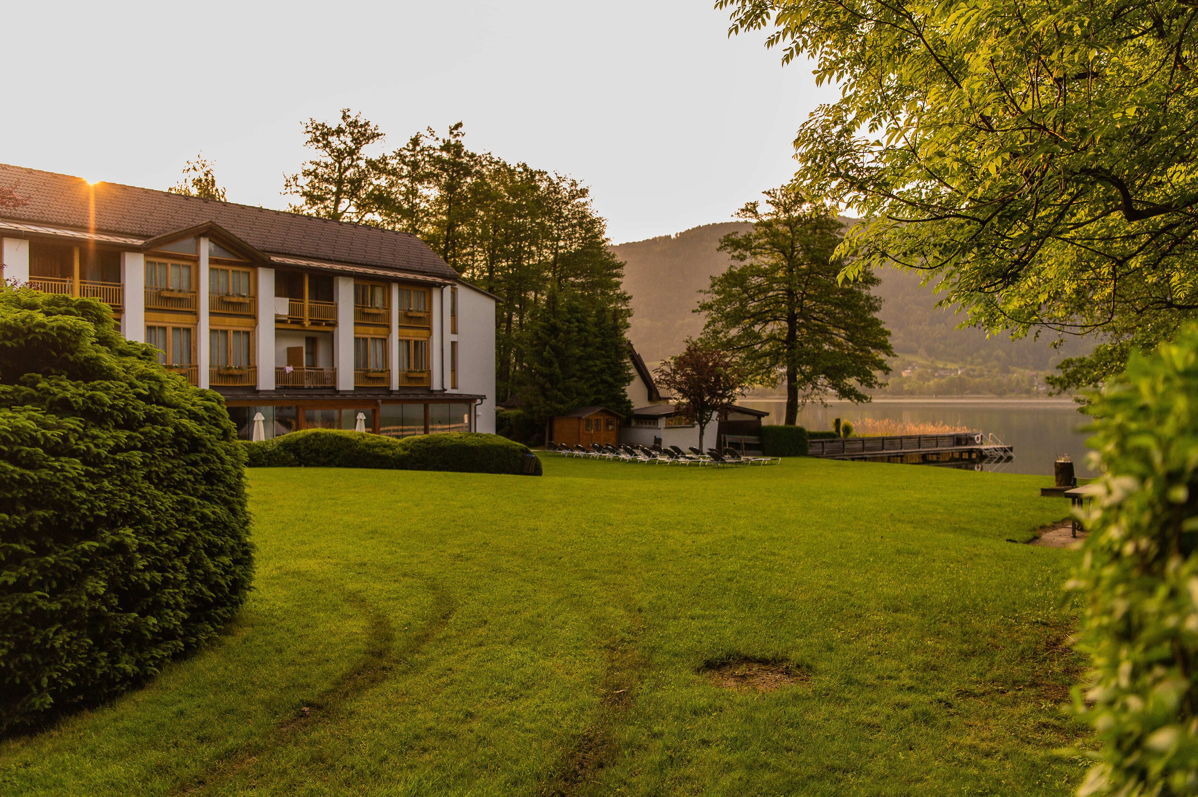 A hotel with a large lawn, a dock, and a mountain backdrop.