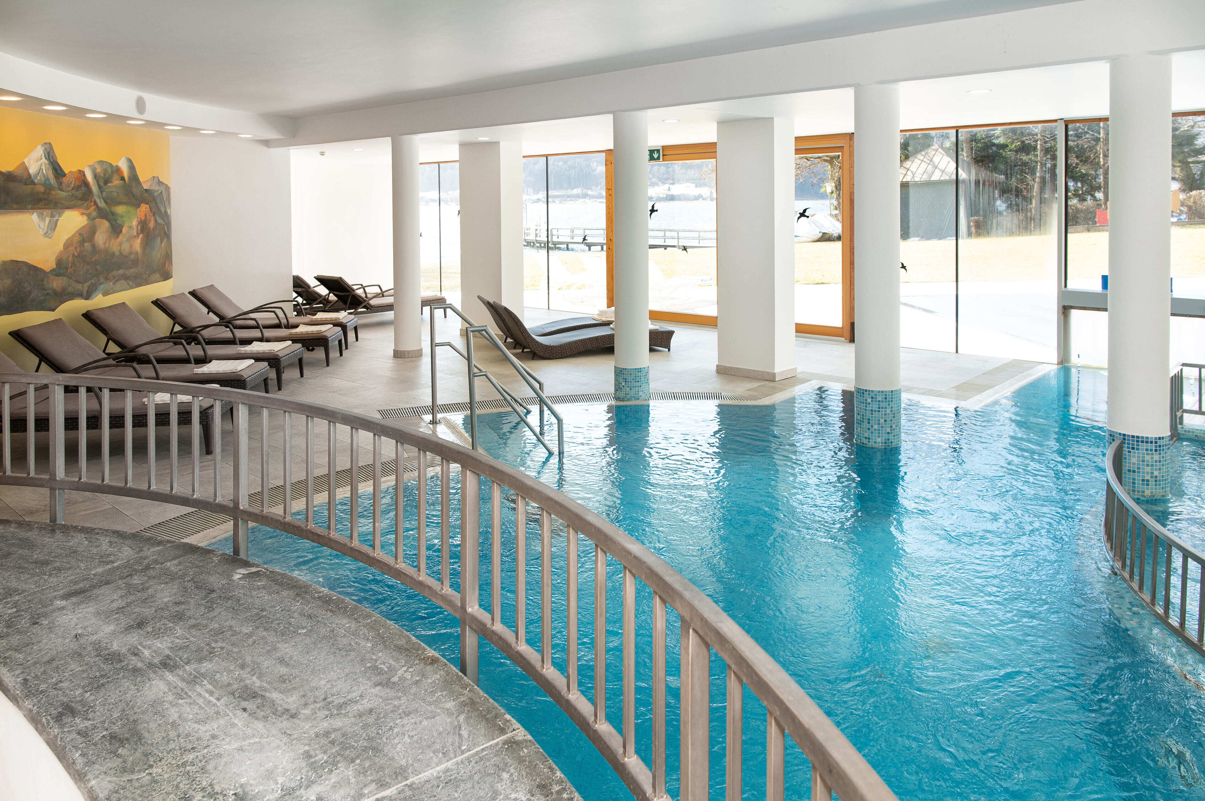Una piscina interior con sillones de descanso y un mural en la pared.