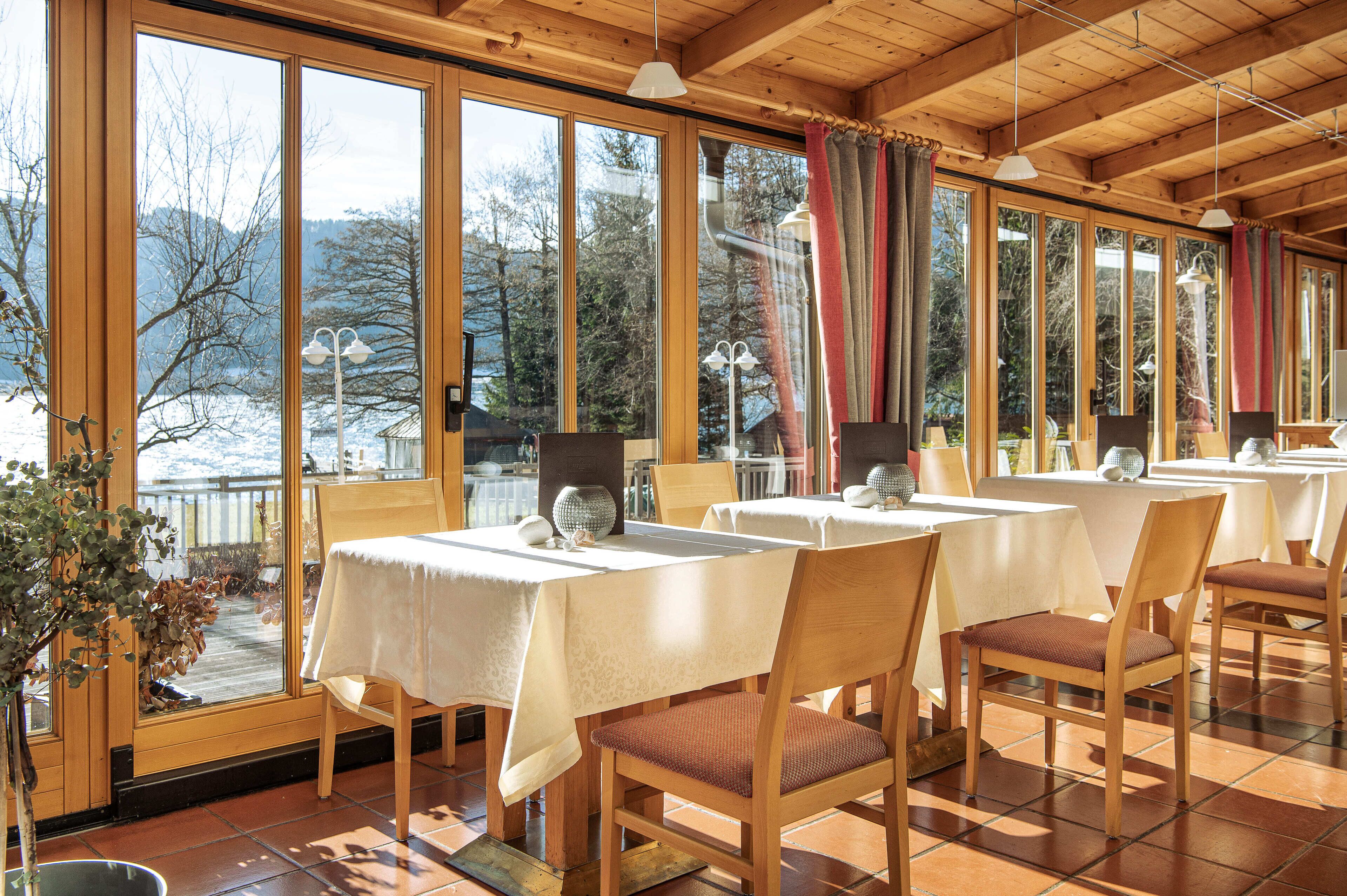 Un restaurante con ventanas amplias, mesas y sillas de madera.