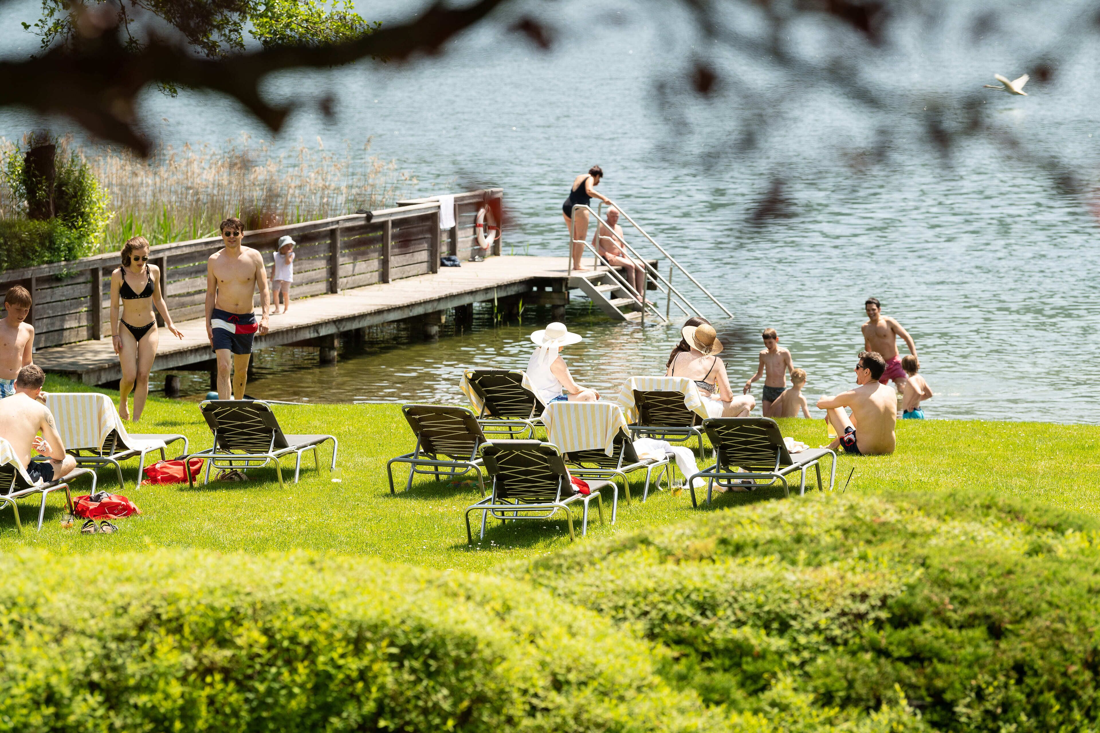 A lakeside setting with lounge chairs and a dock.