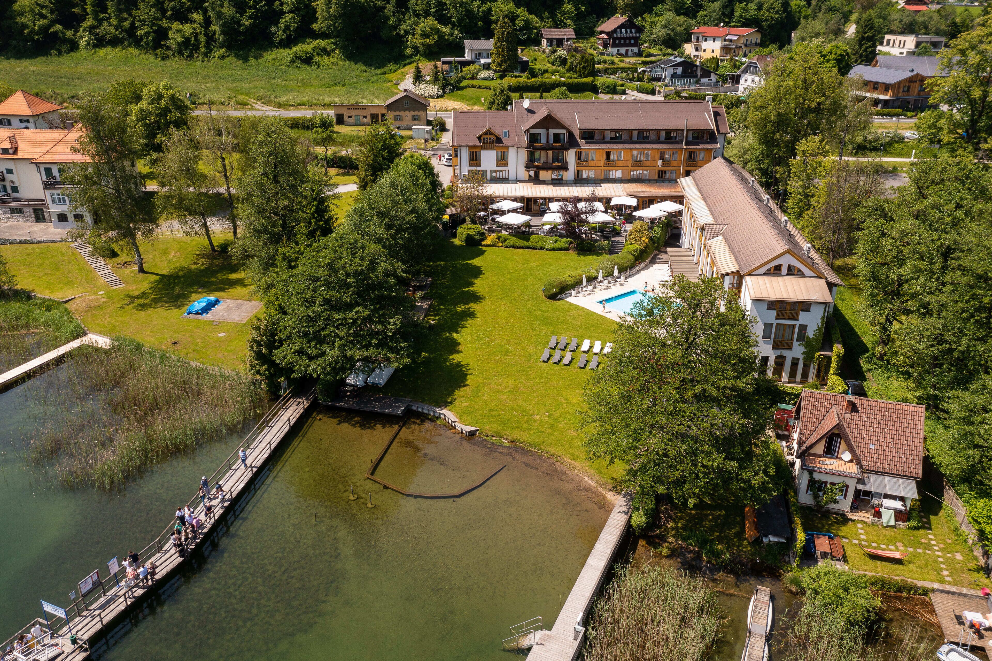 An aerial view of a resort with a swimming pool, a dock, and a large building with multiple balconies.