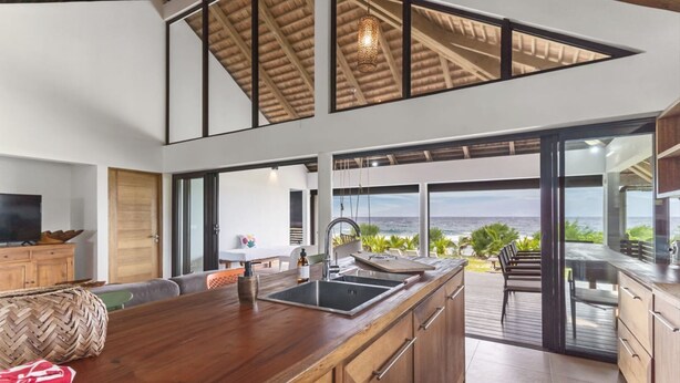 Una cocina moderna con una isla grande, un comedor con vista al océano y un rincón de estar acogedor.