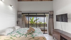 Un dormitorio con cama, televisión, balcón con vistas y techo de madera.