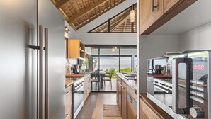 Una cocina moderna con electrodomésticos de acero inoxidable, armarios de madera y vista al océano.