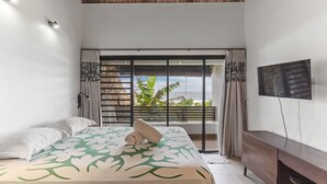 A bedroom with a bed, a TV, a balcony with a view, and a wooden ceiling.