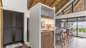 A modern kitchen with a bar area, large windows, and a view of the ocean.