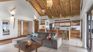 A spacious living area with a sofa, a coffee table, and a kitchen in the background.