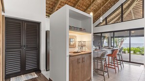 A modern kitchen with a bar area, large windows, and a view of the ocean. - Seaside Haven: Expansive 3BR Villa in Moorea (Moorea)