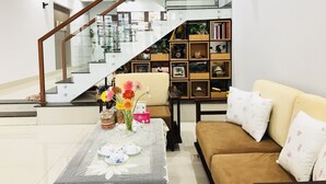 A modern living room with a staircase, a sofa, a coffee table with decorative items, and a bookshelf. - 3-bedroom townhome in enchanting Đà Nẵng with WiFi, AC, fitness room (Đà Nẵng)