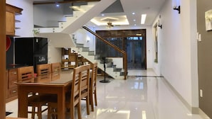 A modern kitchen with a dining area, wooden furniture, and a staircase leading to an upper level. - 3-bedroom townhome in enchanting Đà Nẵng with WiFi, AC, fitness room (Đà Nẵng)
