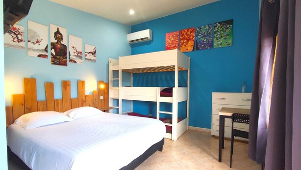 Un dormitorio con una cama litera, un escritorio y una silla. Hay cuadros en la pared y un equipo de aire acondicionado.