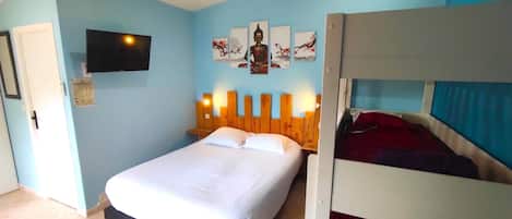 A bedroom with a single bed, a bunk bed, a flat-screen TV mounted on the wall, and a Buddha statue.