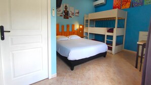 Un dormitorio con cama, literas, una puerta y una pared decorada con obras de arte.