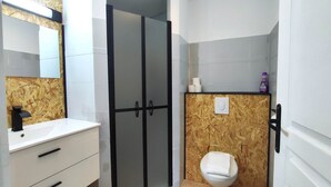 Un baño con un lavabo blanco, un inodoro y una ducha con puerta de vidrio.
