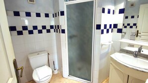 A bathroom with a toilet, a shower enclosure, and a sink. - Chambre Familiale Périgord (VITRAC)