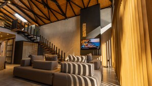 Un salón amplio con un sofá modular grande, una escalera de madera y un televisor de pantalla plana montado en la pared.
