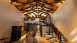 Un interior estilo loft amplio con techo alto, una escalera central y una zona de estar acogedora.