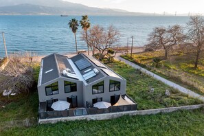 Een modern huis met een schuin dak, grote ramen en een balkon met parasols.