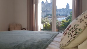 Una camera da letto con un letto, una testiera e una finestra che offre vista su un castello.