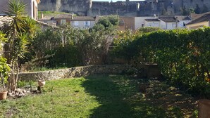 Un cortile con un muro di pietra, piante in vaso e una vista di un castello storico sullo sfondo.