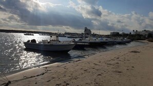 A beach with boats docked along the shore and a distant building.