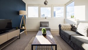 Een moderne woonkamer met een bank, een salontafel, een televisie en een lamp.
