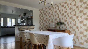 Ruokailutila, jossa on neljälle katettu ruokapöytä, puulattia ja taustalla keittiö.