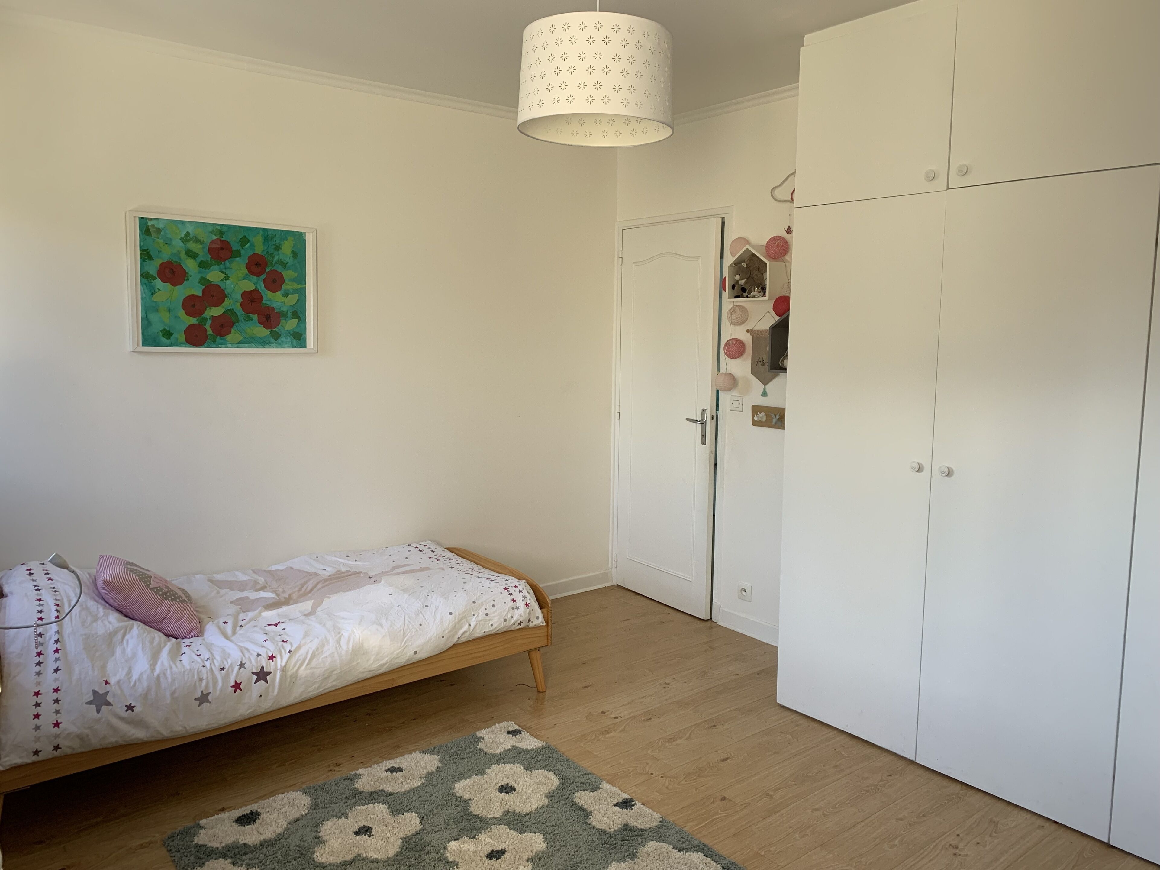 Een slaapkamer met een bed, een kledingkast, een deur en een plafondlamp.