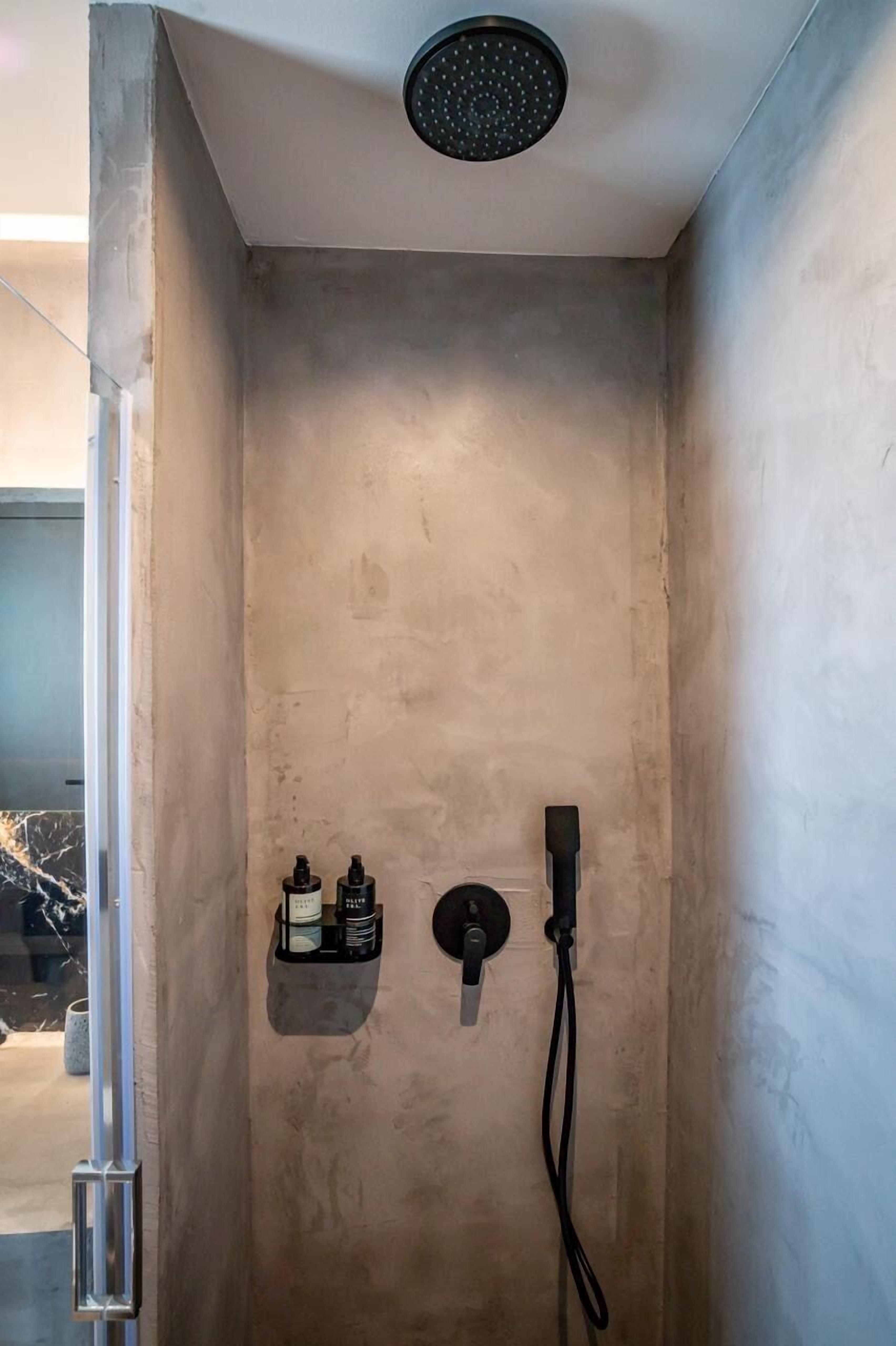 Une douche équipée d’un pommeau de douche à main et d’un robinet fixé au mur.
