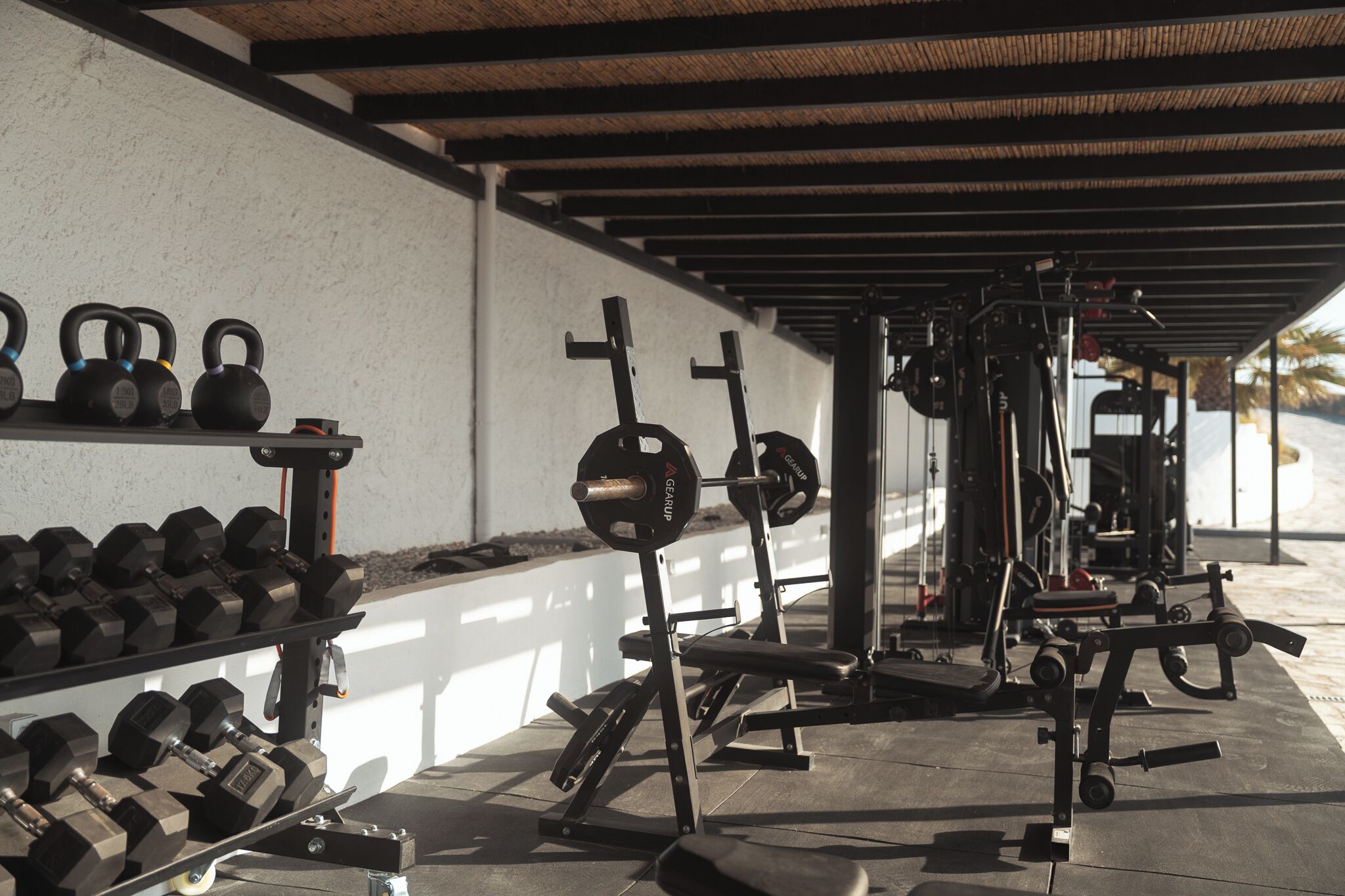 A gym with weightlifting equipment, including kettlebells, dumbbells, and a bench press.