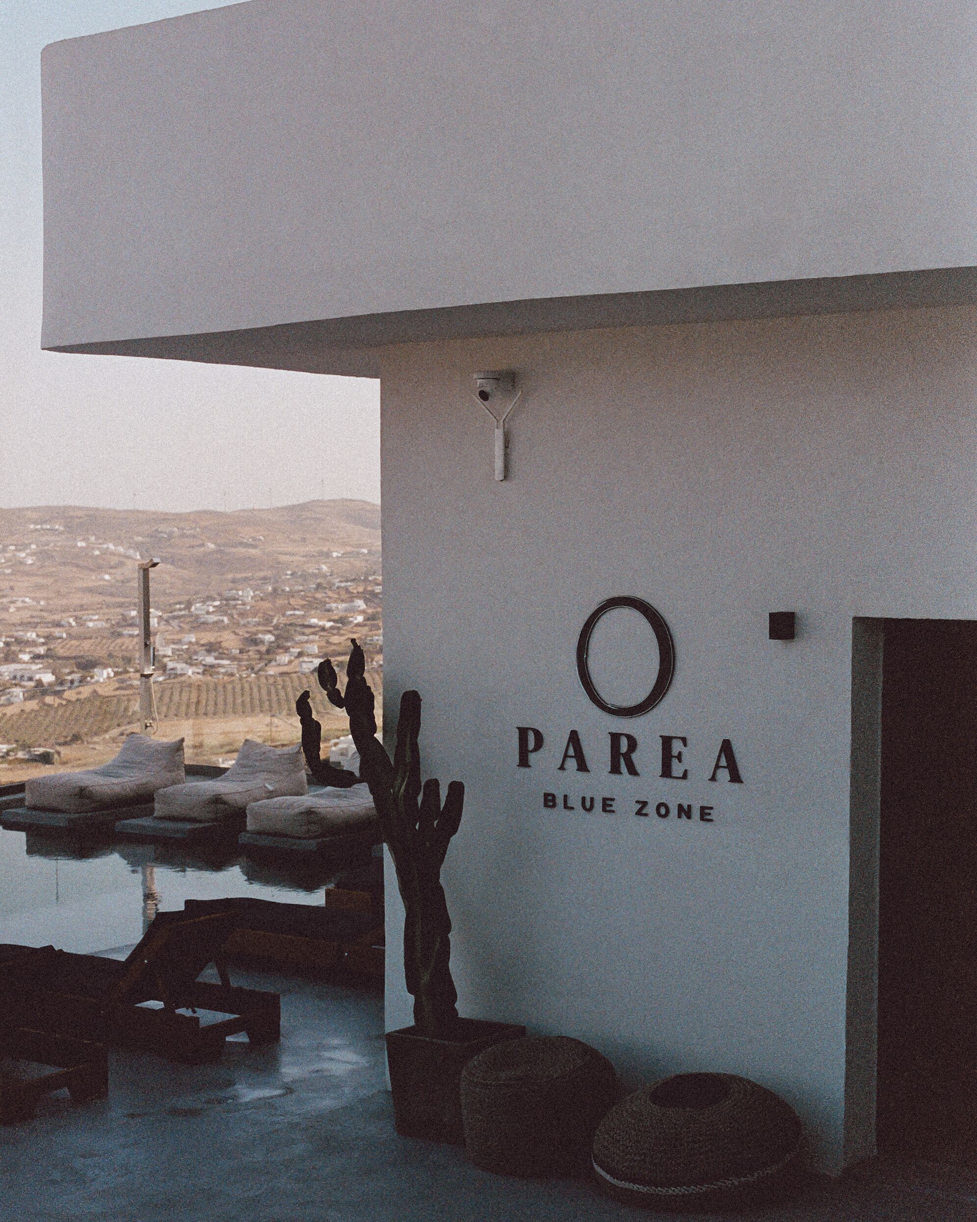 A building with a sign reading "PAREA BLUE ZONE" and a view of a desert landscape in the background.